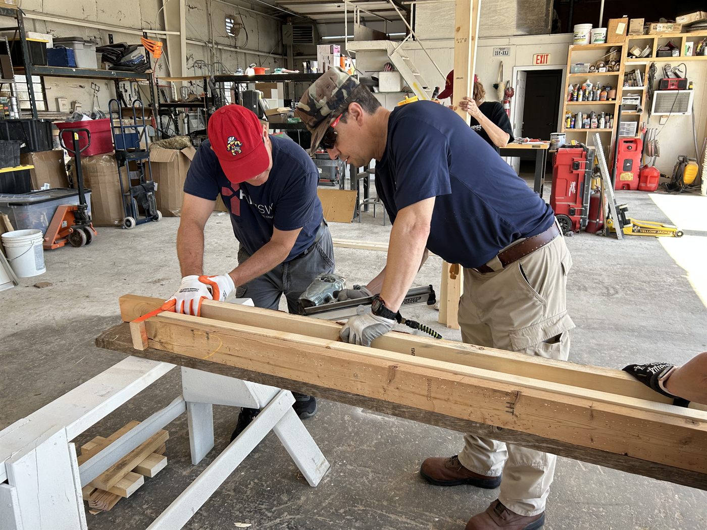 Volunteers cutting lumber together at the Habitat for Humanity workshop