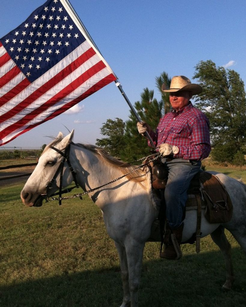 Landrum Leslie Medlock III riding a horse and carrying an American flag