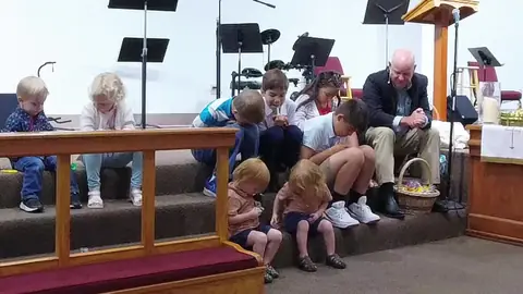 Children praying together at the front of the sanctuary during worship